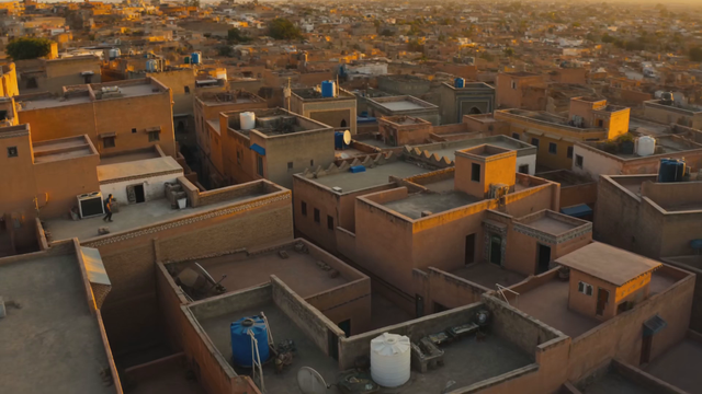Dynamic multi-shot chase: a parkour runner vaults across Moroccan rooftops at dusk, camera whips between wide drone shots and close handheld follows, footsteps and wind audible