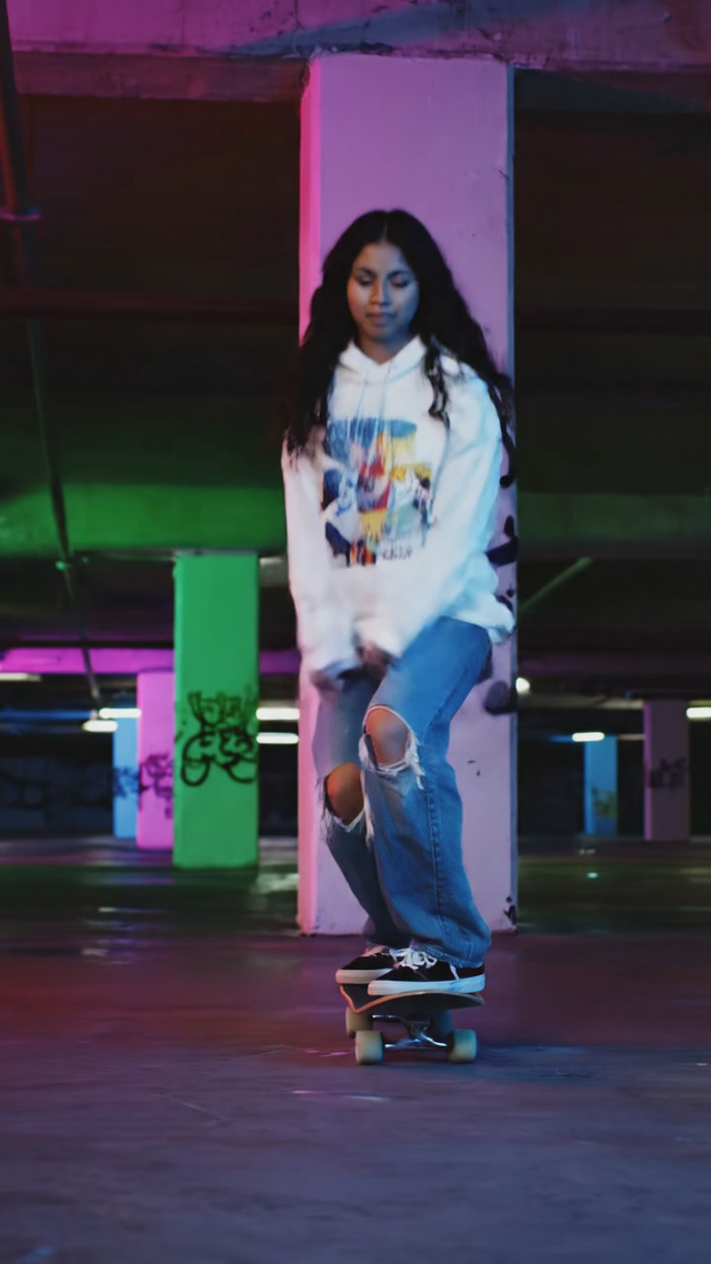 Vertical 9:16 clip: a skateboarder lands a kickflip in a neon-lit parking garage at night, camera low and close, wheels clacking echo, quick whip pan to celebration